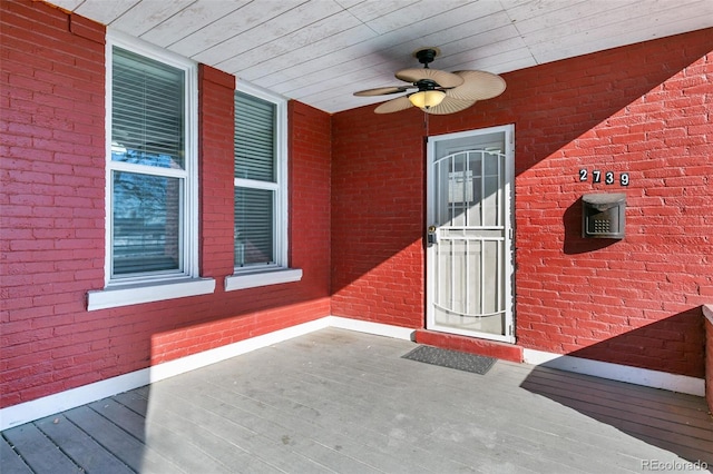 entrance to property featuring brick siding and a ceiling fan