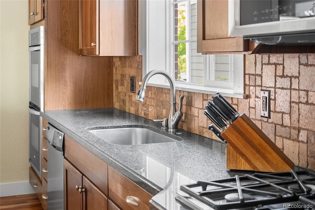 8029 E 23rd Ave, Denver, CO 80238 - kitchen featuring a sink, stainless steel dishwasher, brown cabinets, backsplash, and baseboards