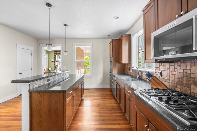 8029 E 23rd Ave, Denver, CO 80238 - kitchen with appliances with stainless steel finishes, a sink, a kitchen island, light wood finished floors, and baseboards