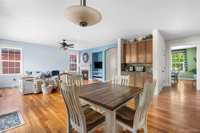 8029 E 23rd Ave, Denver, CO 80238 - dining room with light wood-style floors, ceiling fan, baseboards, and a warm lit fireplace