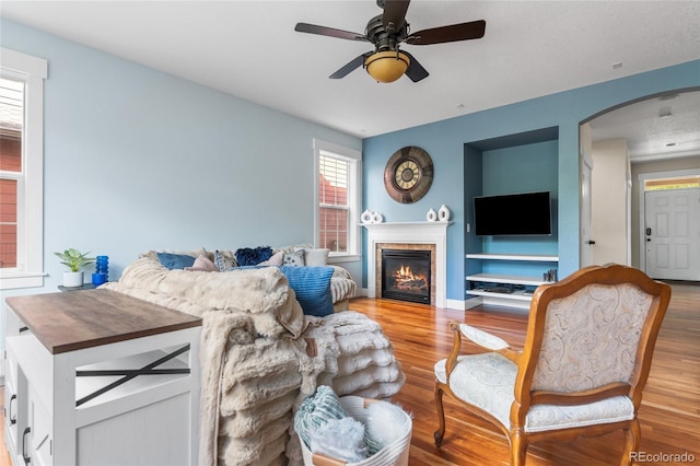 8029 E 23rd Ave, Denver, CO 80238 - living room featuring arched walkways, wood finished floors, a ceiling fan, and a tile fireplace