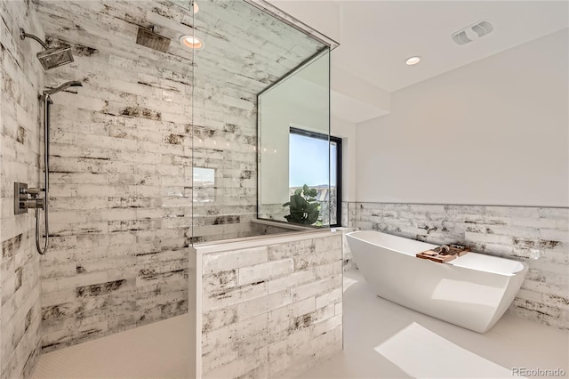 bathroom featuring plus walk in shower and tile walls