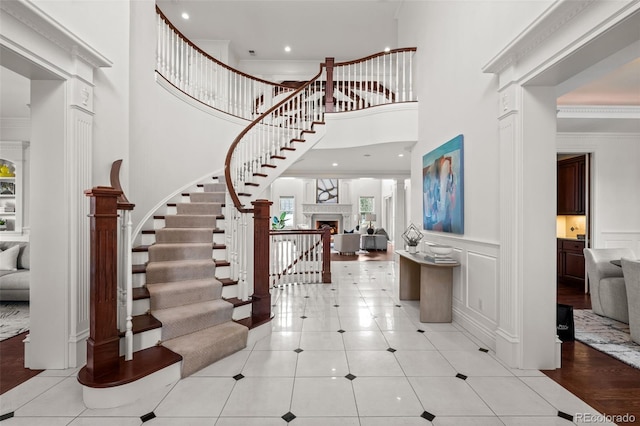 entrance foyer featuring crown molding, a towering ceiling, and light tile patterned floors