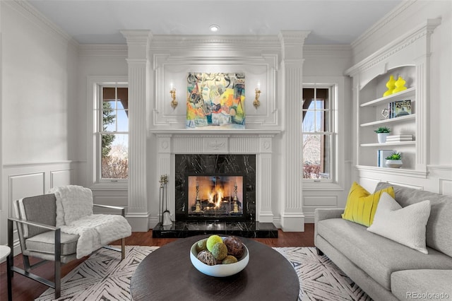 living area with ornamental molding, dark hardwood / wood-style floors, built in features, and a high end fireplace