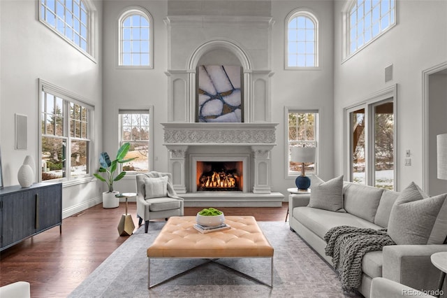 living room with a towering ceiling and dark wood-type flooring