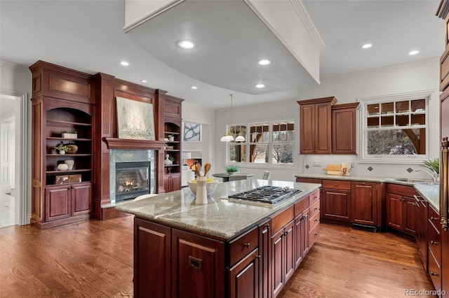 kitchen featuring stainless steel gas stovetop, wood-type flooring, a center island, and pendant lighting