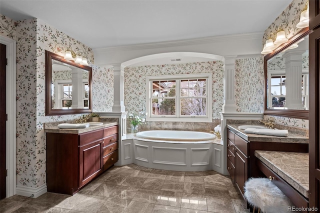 bathroom with a wealth of natural light, decorative columns, a tub to relax in, vanity, and crown molding