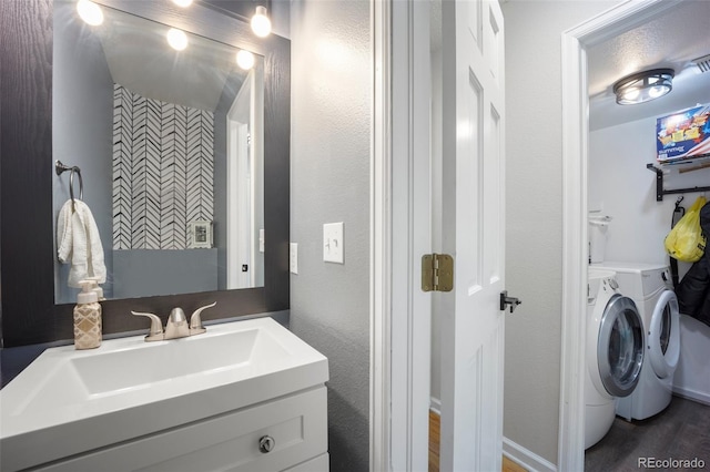 5552 S Lisbon Ln, Centennial, CO 80015 - bathroom featuring washer and dryer, vanity, and wood finished floors