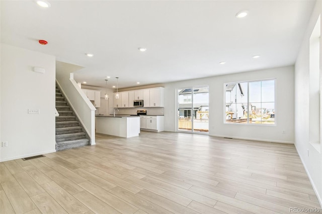 unfurnished living room featuring sink and light wood-type flooring