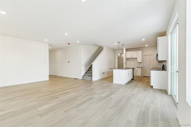 unfurnished living room featuring sink, a wealth of natural light, and light hardwood / wood-style flooring