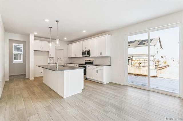 kitchen featuring decorative light fixtures, stainless steel appliances, and white cabinetry