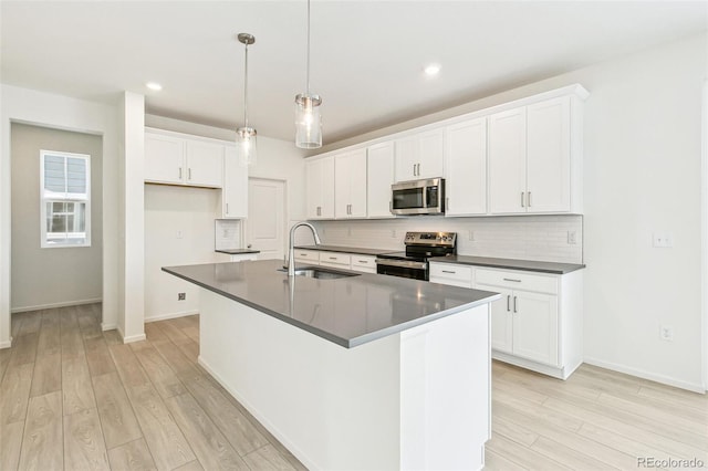 kitchen with stainless steel appliances, sink, a center island with sink, light hardwood / wood-style floors, and white cabinetry