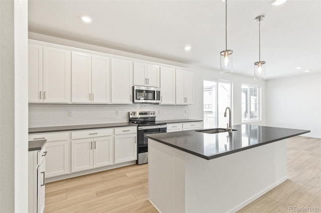 kitchen with sink, white cabinets, stainless steel appliances, and decorative light fixtures