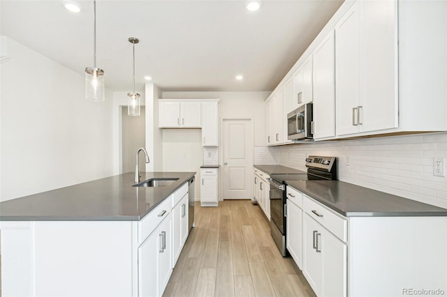 kitchen featuring hanging light fixtures, sink, light wood-type flooring, appliances with stainless steel finishes, and white cabinetry