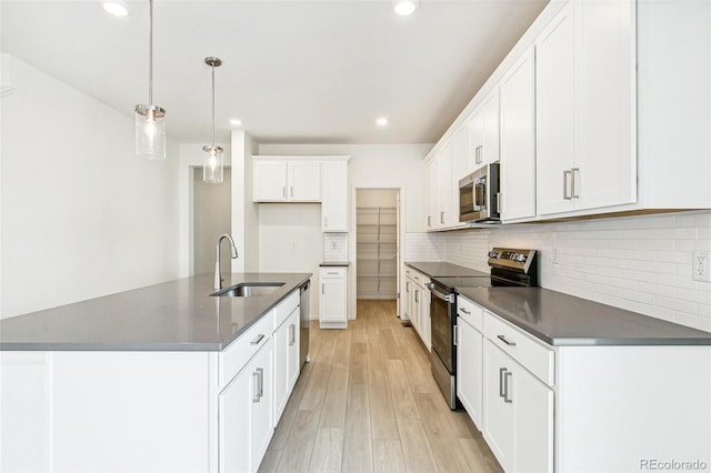 kitchen with pendant lighting, white cabinets, sink, appliances with stainless steel finishes, and light hardwood / wood-style floors