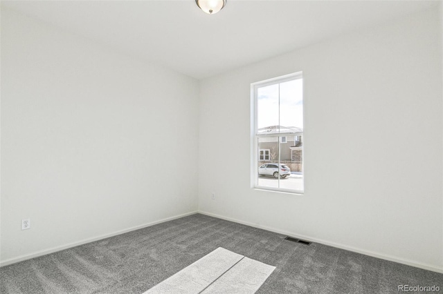 spare room with dark colored carpet