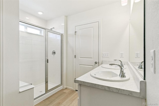 bathroom with wood-type flooring, vanity, and a shower with door