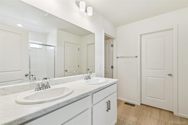 bathroom with hardwood / wood-style floors, vanity, and a shower with shower door