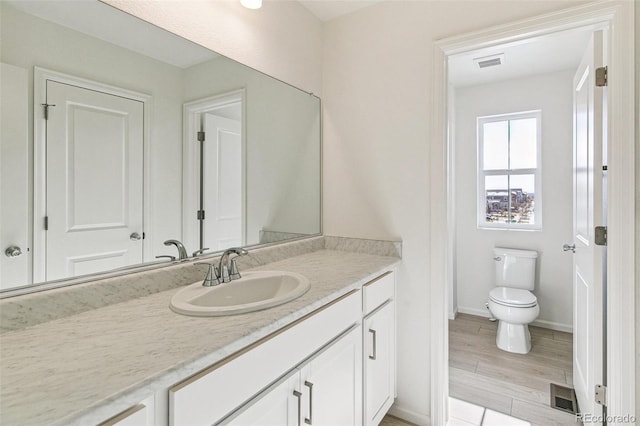 bathroom with hardwood / wood-style floors, vanity, and toilet