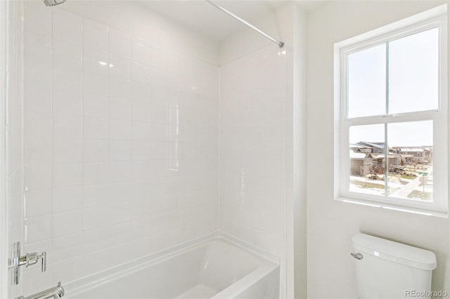 bathroom with a wealth of natural light, tiled shower / bath combo, and toilet