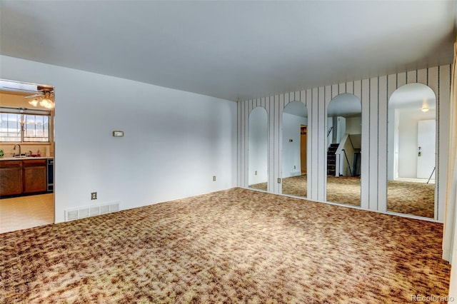 spare room featuring ceiling fan, sink, and carpet floors