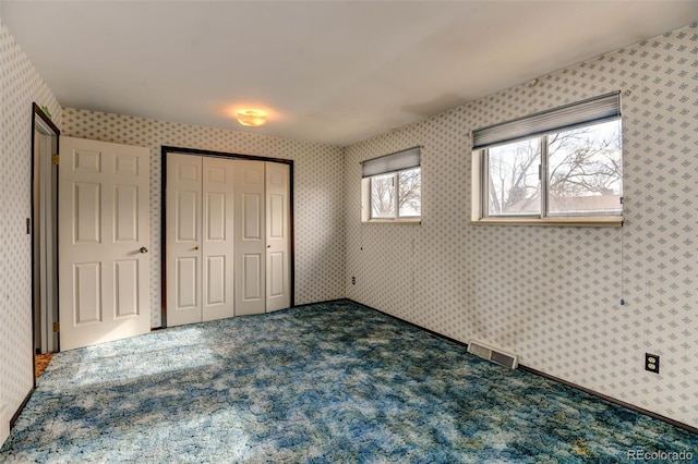 unfurnished bedroom with a closet and dark colored carpet