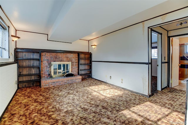 unfurnished living room with a fireplace, a healthy amount of sunlight, and carpet flooring