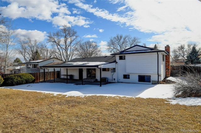 snow covered rear of property with a lawn and a patio area