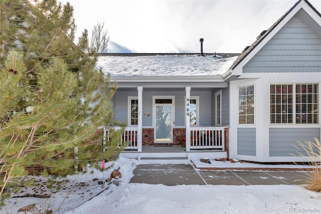 snow covered property entrance featuring covered porch