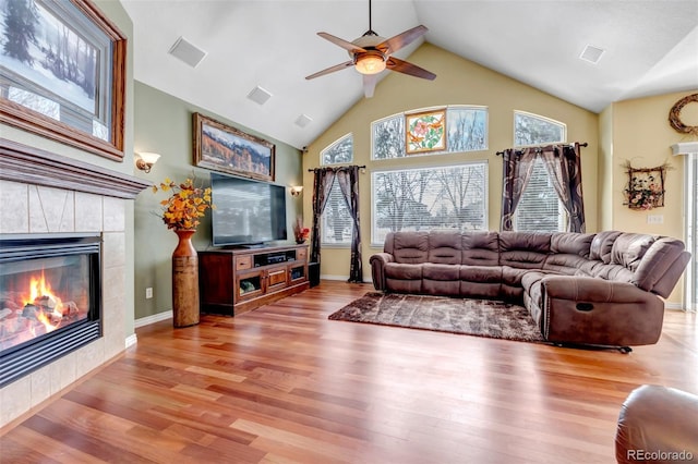 living room with ceiling fan, high vaulted ceiling, light wood-type flooring, and a fireplace