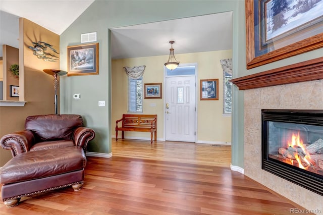 living area featuring wood-type flooring, a fireplace, and vaulted ceiling