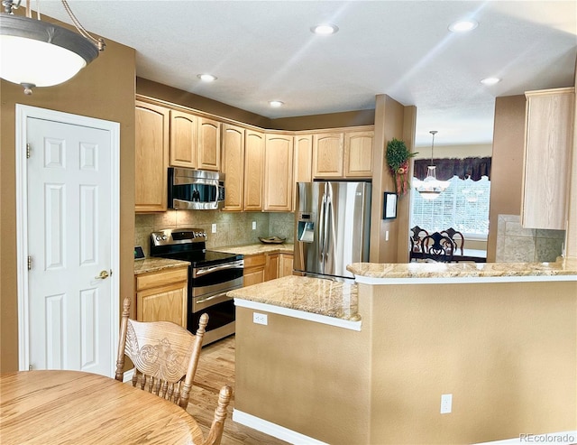 kitchen with pendant lighting, stainless steel appliances, kitchen peninsula, and light brown cabinets