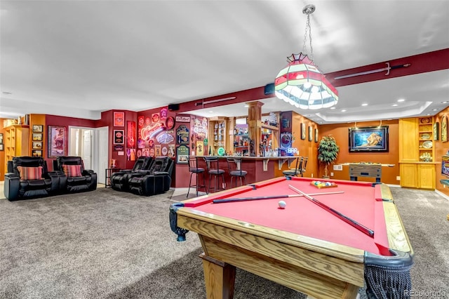 rec room with a tray ceiling, carpet floors, and indoor bar