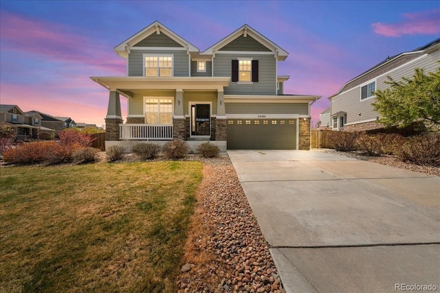 craftsman inspired home with stone siding, covered porch, a garage, a lawn, and driveway