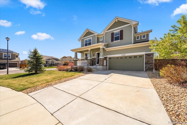 craftsman-style home featuring an attached garage, covered porch, stone siding, a front lawn, and driveway