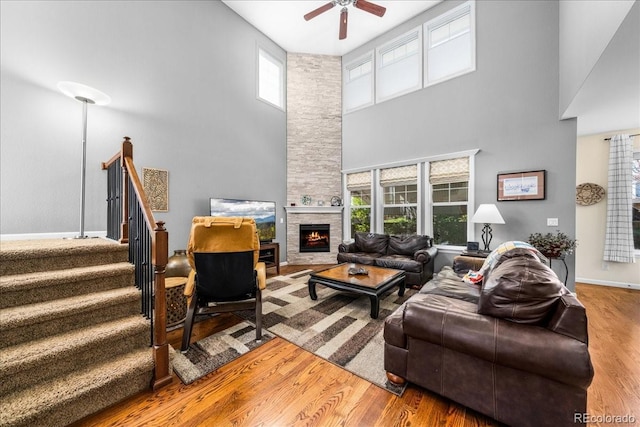 living room featuring a ceiling fan, a wealth of natural light, a high ceiling, and wood finished floors