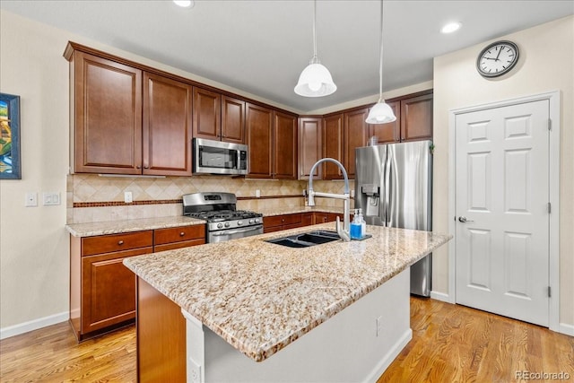 kitchen with a sink, stainless steel appliances, backsplash, and light wood-style flooring