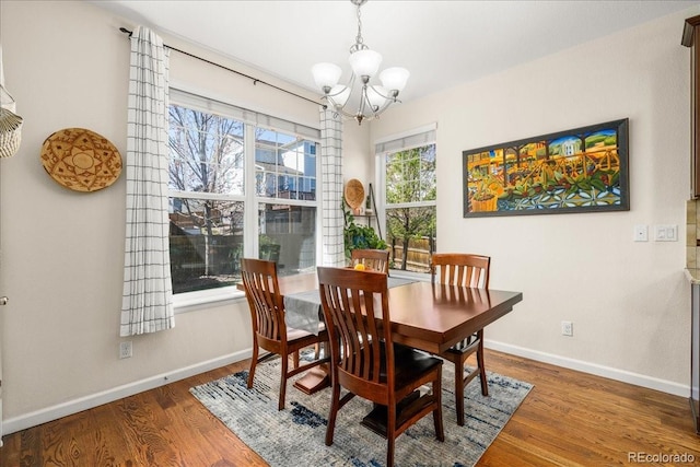 dining area with a chandelier, baseboards, and wood finished floors