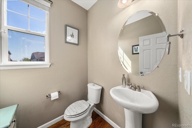 half bathroom featuring toilet, baseboards, a sink, and wood finished floors