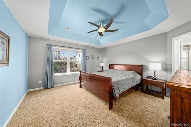 bedroom featuring carpet flooring, a ceiling fan, a tray ceiling, visible vents, and baseboards