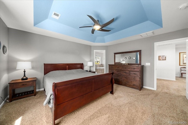 carpeted bedroom with baseboards, a raised ceiling, ceiling fan, and visible vents