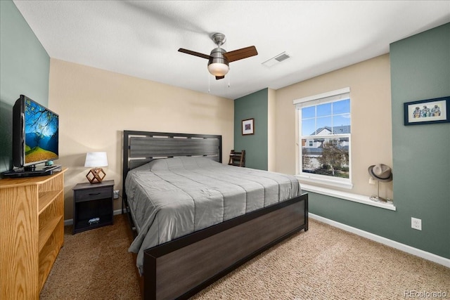 carpeted bedroom with visible vents, baseboards, and a ceiling fan