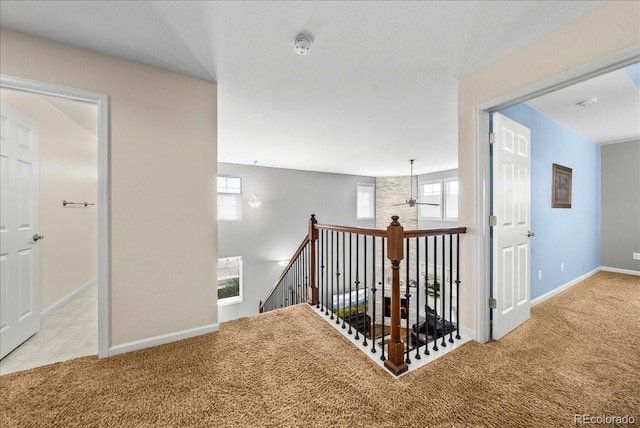 hall with baseboards, carpet flooring, and an upstairs landing