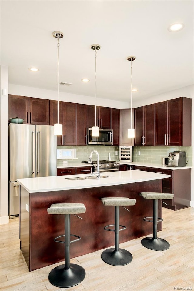 kitchen with stainless steel appliances, backsplash, a kitchen breakfast bar, and light wood-style floors