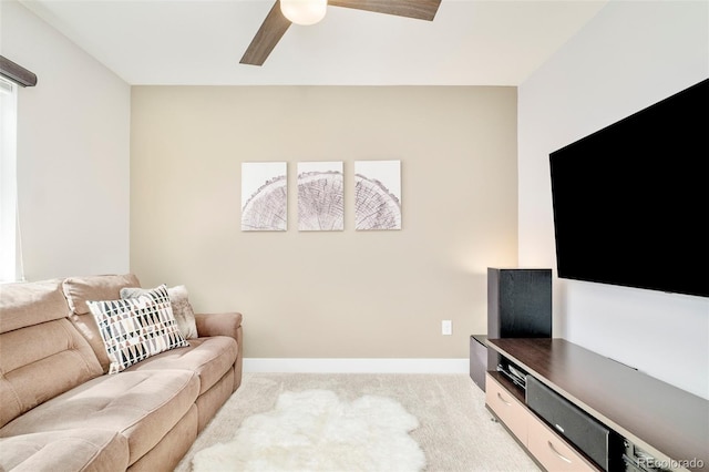 living area featuring light colored carpet, baseboards, and a ceiling fan
