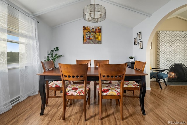 6854 S Willow St, Centennial, CO 80112 - dining area with arched walkways, light wood-type flooring, baseboards, lofted ceiling with beams, and an inviting chandelier