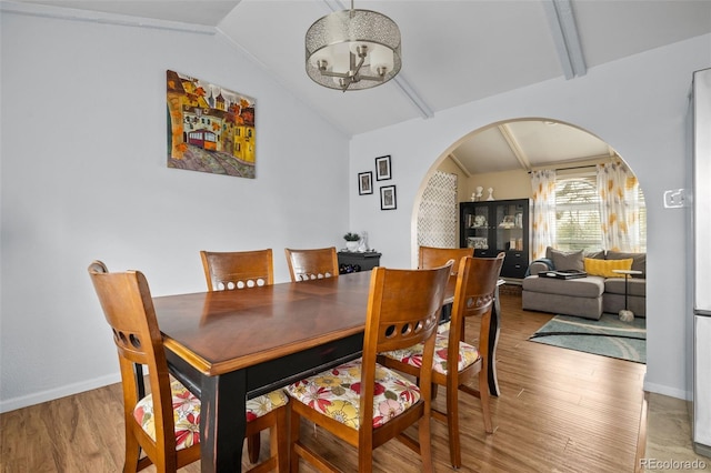 6854 S Willow St, Centennial, CO 80112 - dining space with a notable chandelier, lofted ceiling with beams, arched walkways, baseboards, and light wood-type flooring