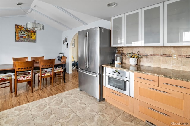 6854 S Willow St, Centennial, CO 80112 - kitchen featuring lofted ceiling, glass insert cabinets, arched walkways, backsplash, and stainless steel appliances