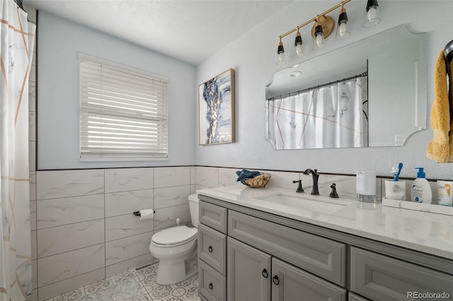 6854 S Willow St, Centennial, CO 80112 - full bathroom featuring vanity, toilet, tile walls, a wainscoted wall, and tile patterned floors