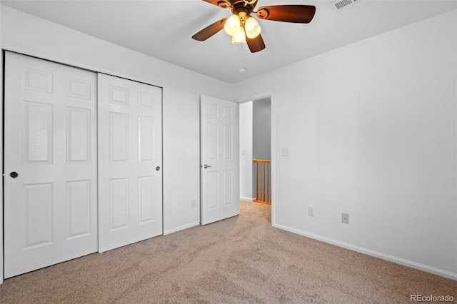 unfurnished bedroom featuring ceiling fan, light colored carpet, and a closet